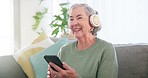 Senior woman, phone and music headphones in home for listening to audio, radio and podcast on sofa. Happy elderly lady dancing with smartphone for streaming sound online, media app and subscription 