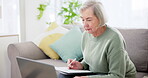 Laptop, writing and documents for pension with an old woman in the living room for retirement planning. Computer, accounting and investment for finance with a senior adult on a sofa in her home