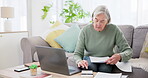 Laptop, writing and calculator for finance with an old woman in the living room for retirement planning. Computer, documents and investment for pension with a senior adult on a sofa in her home