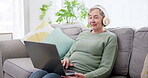 Music, laptop and relax with old woman on move for watching movie, streaming and social media. Online radio, technology and internet with senior person and headphones in living room at home for audio