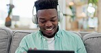 Home, headphones and black man on a couch, tablet and streaming music with connection, smile and sound. African person, headset and happy guy on a sofa, technology and listening to audio with radio