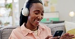 Music, living room and singing woman at home with headphones and audio in a lounge. Happy, smile and excited African female person on a sofa with freedom, web radio and hearing a fun song in a house