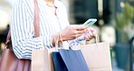 Woman, phone and hands with shopping bag in city, communication or travel in outdoor networking. Closeup of female person or shopper typing, texting or chatting on mobile smartphone app in urban town