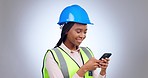 Woman, helmet and engineering with phone in studio for industrial development, reading notification or update on grey background. African architect, construction and laughing for typing on smartphone