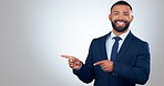 Pointing, happy and face of businessman in a studio with mockup for marketing or advertising. Smile, portrait and young male lawyer from Mexico with show gesture for mock up space by white background