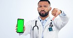 Phone, green screen and face of doctor in studio with thumbs down hand gesture for healthcare. Mockup, technology and portrait of male medical worker with disagreement expression by white background.