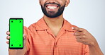 Man, phone and hand pointing to green screen in studio for marketing or advertising tracking markers on white background. Smile, person and smartphone with product placement for social media website