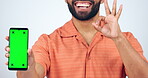 Phone, green screen and man with yes, ok and success hands of social media subscription or marketing in studio. Happy person, mobile app and certified or emoji on tracking marker and white background