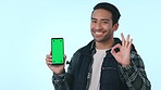 Happy asian man, backpack and pointing to phone, green screen or mockup in advertising against a studio background. Male person or tourist show OK sign for perfect mobile smartphone app or display