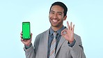 Business man, green screen phone and ok emoji, smile or excited face in studio by blue background. Entrepreneur, smartphone and point for feedback, review or good service with mockup space for logo