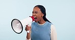 Black woman, megaphone and shouting in protest, voice or announcement against a studio background. Frustrated African female person or activist screaming in bullhorn or loudspeaker on mockup space