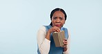 Woman, popcorn and horror in movie, studio or cinema with eating, fear and shock by blue background. African girl student, food and snack with scared face, streaming or watching tv film with surprise