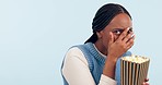 Scared, popcorn and face of a black woman for a movie, horror or hiding on a studio background. Surprise, fear and portrait of an African girl or person eating a snack with reaction to a film