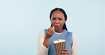 Face, funny and black woman with popcorn, smile and laughing on a blue studio background. Portrait, African person or model with humor, comedy and snack with expression, silly or goofy with happiness