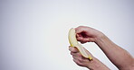 Hands, diet and a person peeling a banana in studio on a gray background closeup for health or nutrition. Fruit, food or healthy eating and a vegan adult with fresh produce for hunger or potassium