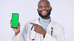 Green screen, phone and face of doctor in studio with mockup space for advertising or marketing. Pointing, tracking markers and portrait of black man medical worker with cellphone by white background