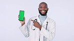 Green screen, pointing and doctor with phone in studio with mockup space for medical advertising. Smile, tracking markers and face of black man healthcare worker with cellphone by white background.