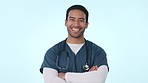 Face, doctor and man with arms crossed, smile and surgeon on a blue studio background. Portrait, medical professional and model with healthcare, career or physician with uniform, happy or stethoscope