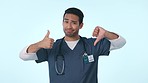 Confused, decision and Asian man in studio with hands gesture for choice, option and doubt. Healthcare, thumbs up and down and portrait of health worker unsure for medical service on blue background
