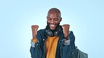 Black man, headphones and celebration in studio for exam results, success or promotion by blue background. African gen z student, winner or fist in air for goal, achievement or scholarship for future