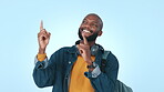 Black man, pointing up and advertising with OK sign, promotion and agreement isolated on blue background. Mockup space, headphones and music ads with support, announcement and show in a studio