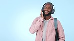 College student, dancing and listening to music with headphones in studio. Happy, young and black person streaming audio sound with backpack for university education and relax on a blue background