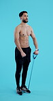 Exercise, resistance and a shirtless man on a blue background in studio for a full body workout. Fitness, strong or muscle with a young athlete or bodybuilder training his body on a vertical backdrop