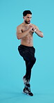 Fitness, resistance and a shirtless man on a blue background in studio for a full body workout. Exercise, strong or muscle with a young athlete or bodybuilder training his body on a vertical backdrop