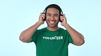 Volunteer, music headphones and a man in studio for community service, charity and social welfare. Face of a happy person listening to audio on a blue background for motivation and volunteering