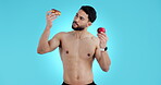 Nutrition, man and shirtless with apple and donut for healthcare choices or option in studio on blue background. Fitness, portrait and person with healthy food, fruit or diet advice for wellness
