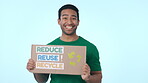 Green, poster for recycling and a volunteer man on a blue background in studio to promote conservation on earth day. Portrait, smile and charity for global warming, climate change or sustainability