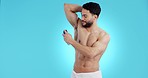 Hygiene, armpit and man with deodorant, clean and grooming with a smile and morning routine in studio. Blue background, male person and shower with cosmetics, muscle and skincare with body perfume 