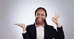 Okay sign, pointing and business black woman in studio for promotion, advertising and presentation. Happy, professional and portrait of worker on gray background for agreement, approval and yes emoji