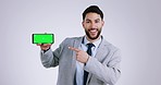 Business man, green screen smartphone and studio with point, face or review by white background. Entrepreneur, mobile phone and mockup space with tracking markers for brand, logo or promotion for app