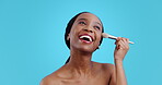 Beauty, makeup and brush with face of black woman in studio for cosmetics, tools and product. Foundation, salon and powder with person on blue background for skincare, treatment and dermatology