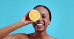 Black woman, lemon and beauty for face, studio and excited smile for natural product by blue background. Happy girl, model and citrus fruit for vitamin c, transformation and dermatology for skincare