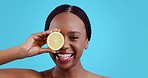 Skincare, lemon and black woman face with laughing, smile and organic dermatology in studio. Blue background, happy female person and skin glow with fruit detox and health food with wellness shine