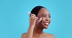 Skincare, rose quartz and black woman with face roller, smile and dermatology in studio. Blue background, happy African female person and skin glow with cosmetics and makeup with wellness and shine