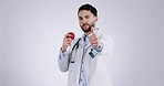 Doctor man, thumbs up and apple in studio for eating, diet and healthy choice by white background. Medic, nutritionist and fruit with review, promotion or feedback with vote, decision or vegan food