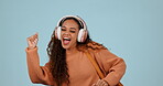 Headphones, dancing and happy woman travel with music, radio and isolated in a studio blue background. Happiness, joy and young person streaming audio for energy movement and celebration with smile