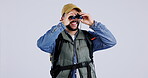 Binocular, man and travel with hiking, backpack and wildlife watching of a traveler on holiday in studio. White background, male person and adventure with animal and bird search of camper on journey