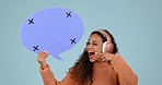 Speech bubble, pointing and woman with headphones in studio for voice, music or social media.Young person with announcement, wow feedback and streaming faq on a blue background with tracking markers