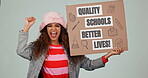 Fist, politics or education and a woman student on a gray background in studio with a cardboard poster. Portrait, justice or government and a young university pupil in protest for quality school