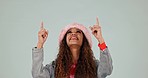 Fashion, pointing up and woman in studio with trendy hat excited for deal, promotion and sale. Advertising, hand gesture and portrait of person for news, announcement and discount on gray background