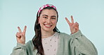 Face, happy woman and sign of peace in studio of winning, vote or celebrate success on blue background. Portrait, young gen z model and hands show v icon, symbol or emoji of freedom, support or pride