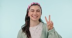 Face, happy and woman with peace in studio for winning, vote or celebrate success on blue background. Portrait, young gen z model and hands show v sign, symbol and emoji for freedom, support or pride