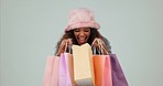 Happy, excited and woman with bags, shopping and client with retail on a blue studio background. Portrait, person and client with excitement, luxury clothes and expensive items with wow and surprise