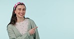 Woman, happy and face with pointing to show promotion, deal and advertising presentation in studio. Female person smile, sale and portrait with promo and information with choice and blue background