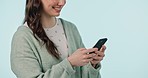 Woman, hands and typing with phone in studio, reading social media and digital notification on blue background. Smartphone, happy model and closeup to search multimedia, download mobile app or mockup
