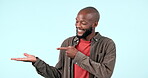 Pointing, face or happy black man by sale, discount deal or retail offer for studio space advertising. Mockup, hand palm or excited person with mockup space, news or menu promotion on blue background